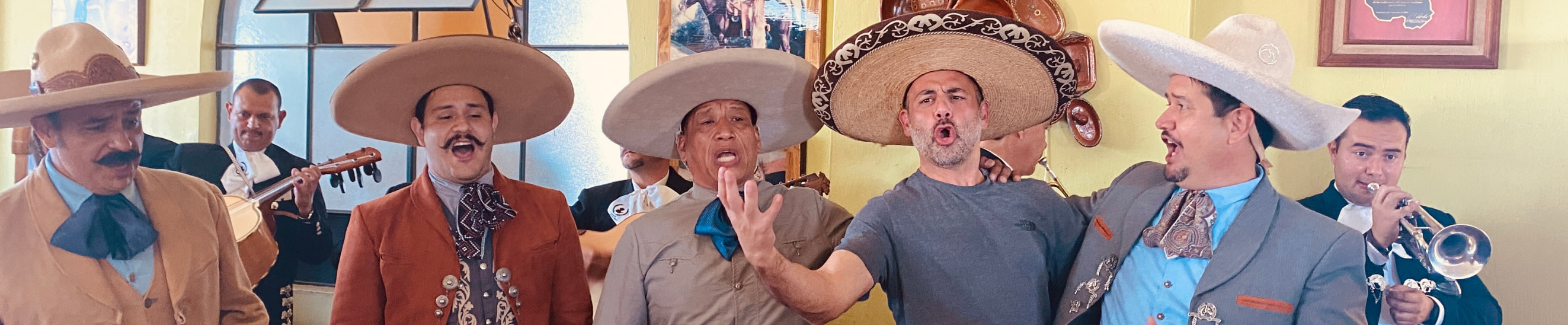 Mariachi en balcón del Lienzo Charro con pareja folklórica en escenario abajo