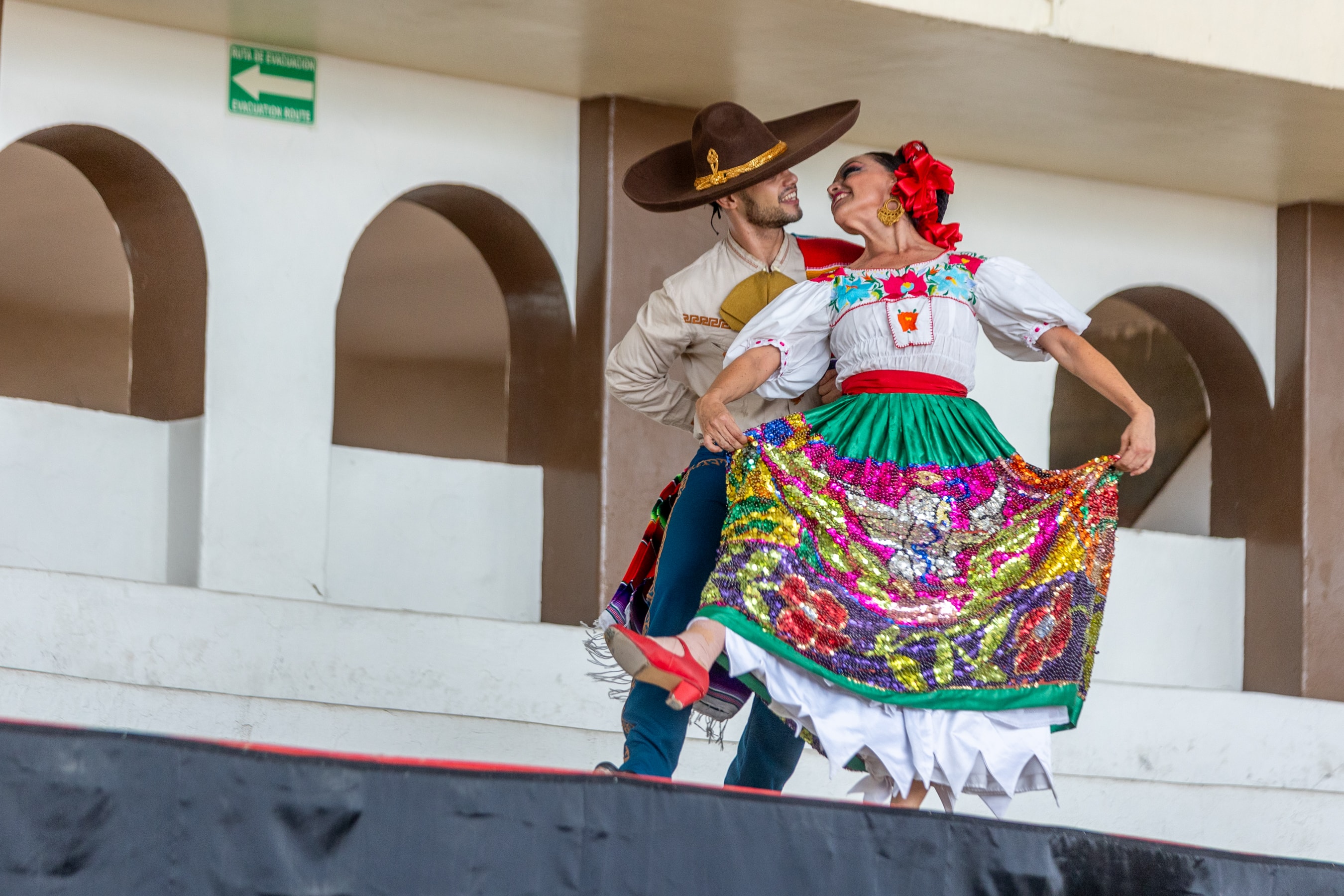 Pareja de baile folklórico con traje bordado colorido actuando en el Lienzo Charro de día