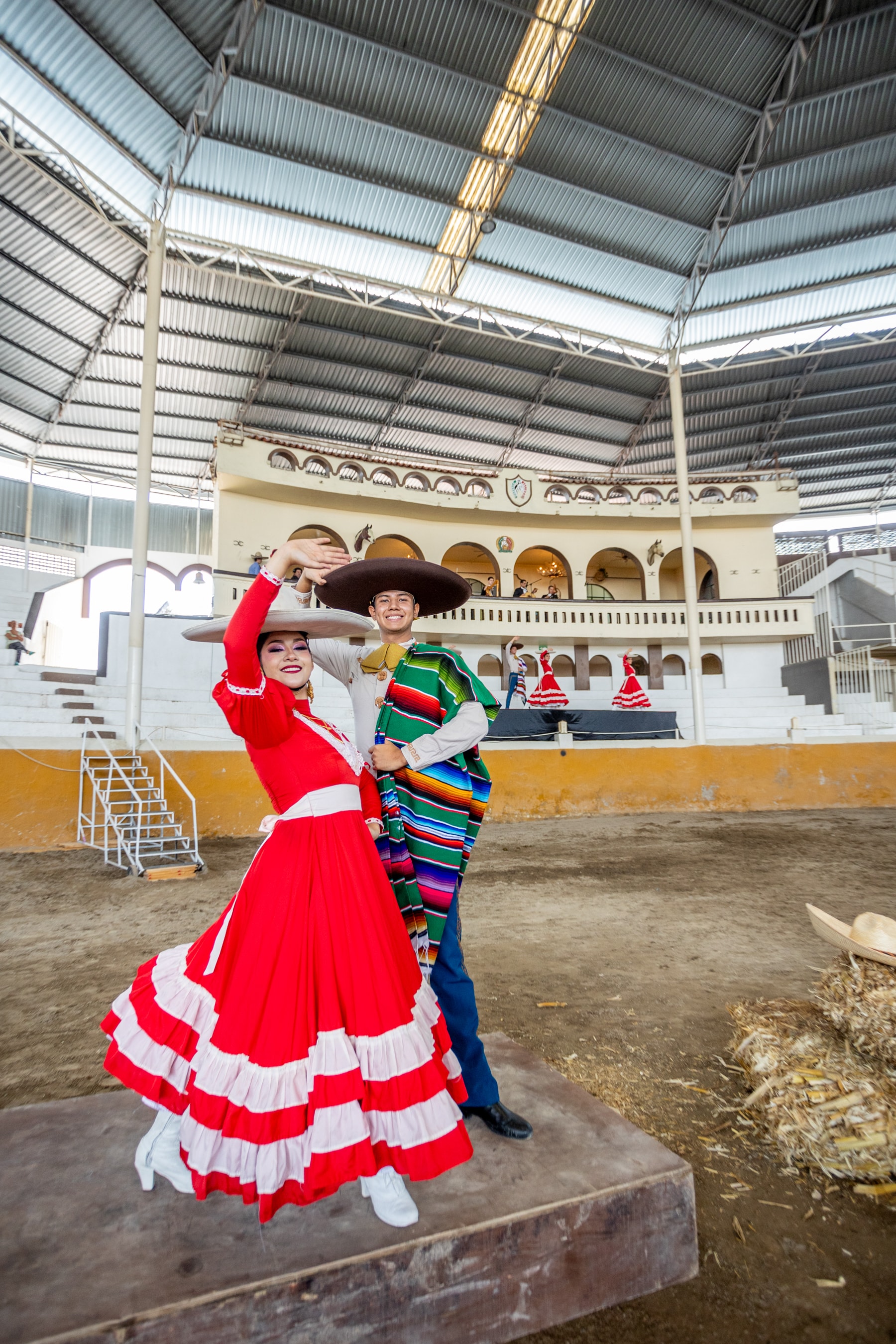Pareja folklórica con vestido rojo y sarape multicolor posando en el Lienzo Charro