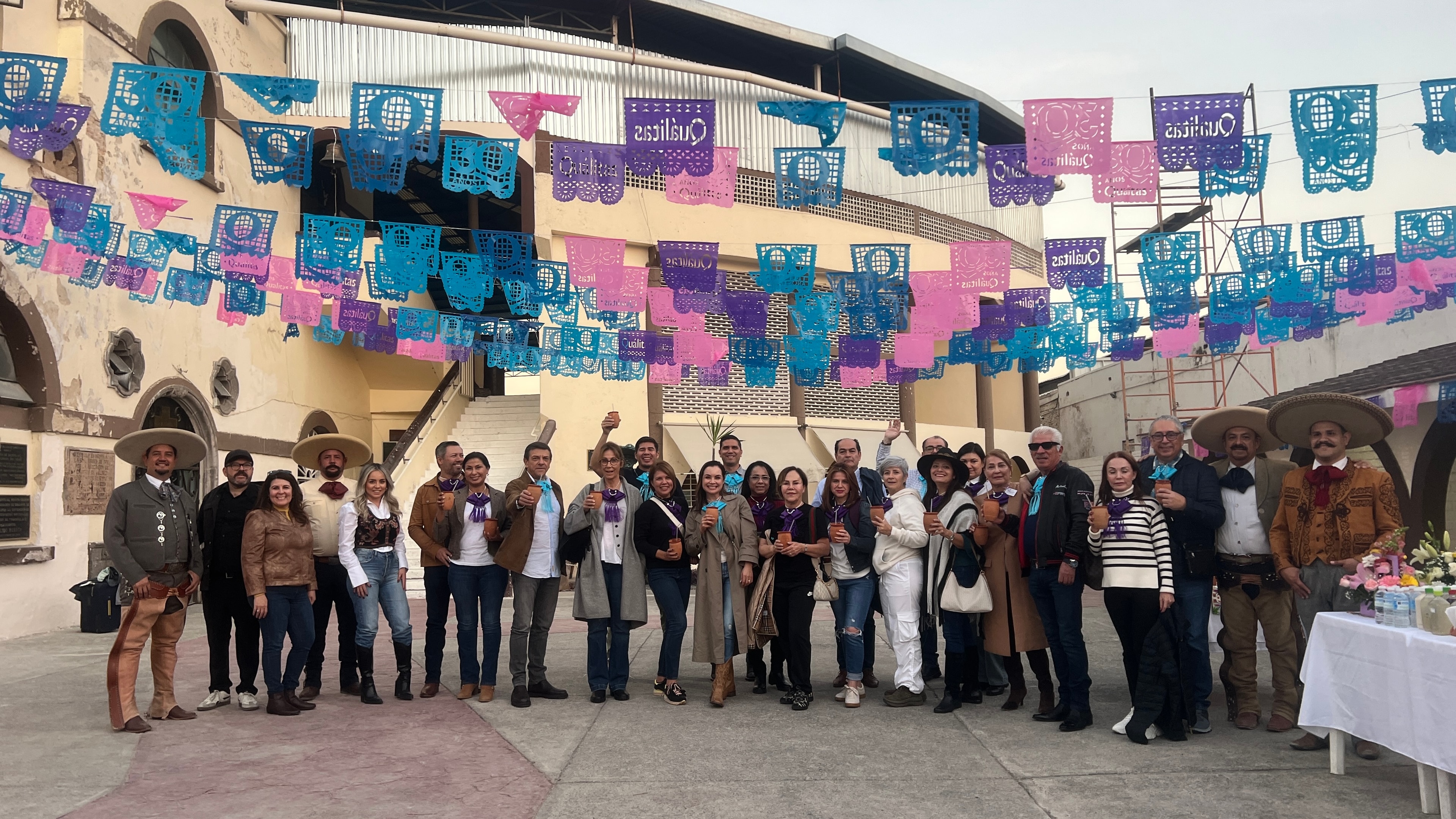 Foto grupal con charros bajo papel picado en el Lienzo Charro